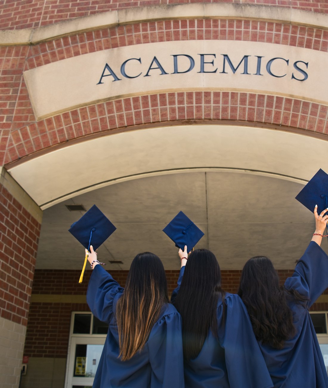 Graduandos celebrando bajo un arco que dice Academics